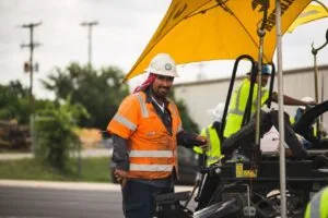 man with hard hat in orange vest on top of fresh concrete