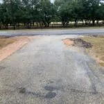 asphalt driveway with potholes and patching needs