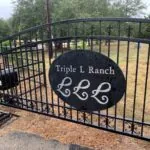 metal ranch entrance gate with Triple L Ranch sign and paved driveway