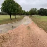 damaged asphalt driveway with erosion and exposed dirt base