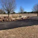 curved asphalt driveway with landscaping and stone edging