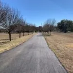 finished asphalt driveway extending through rural landscape