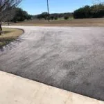 smooth black asphalt driveway connected to concrete apron