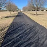 long newly paved asphalt driveway through rural property