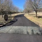 fresh asphalt paving at gated ranch entrance with cattle guard