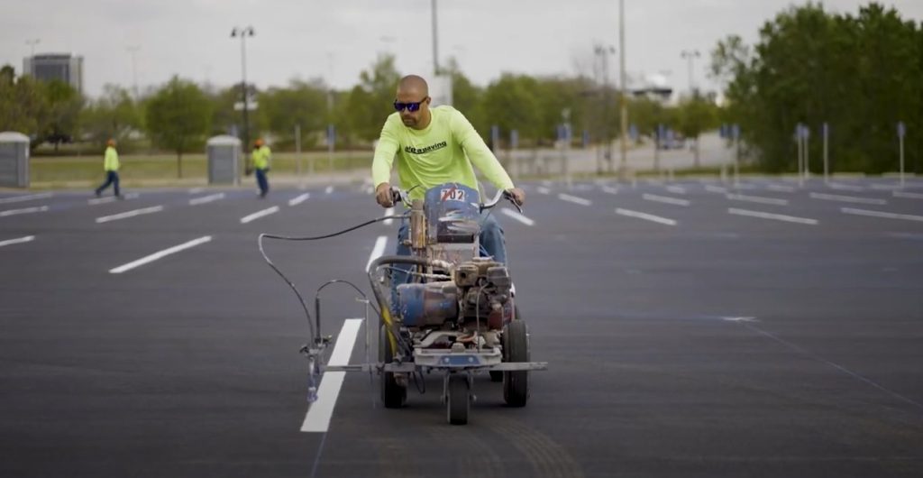 concrete contractor painting striping paint in freshly paved parking lot