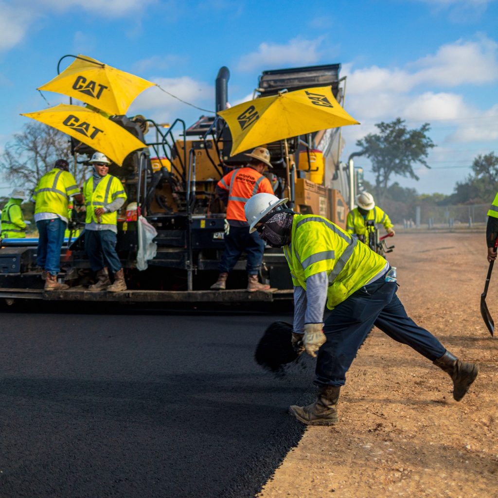 Alpha paving crew laying asphalt next to large machinery