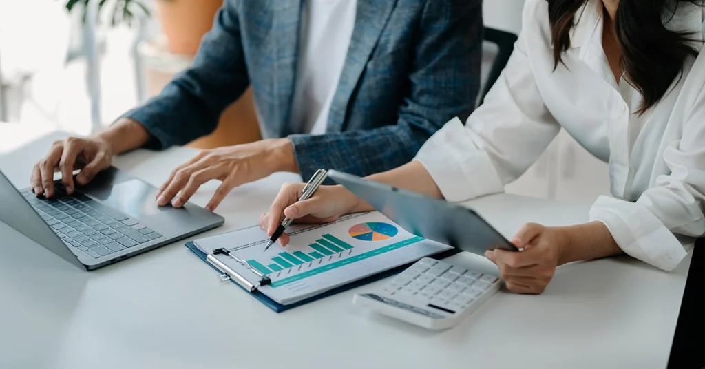 close up of two people looking over their budget with a laptop an da calculator