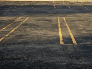 Fading pavement striping on worn asphalt parking lot surface at commercial property