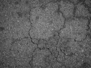 Close-up of cracked asphalt surface showing pavement wear