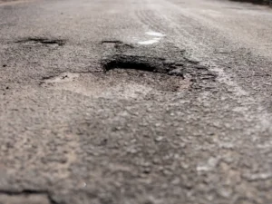 Pothole damage on worn asphalt pavement in commercial parking area
