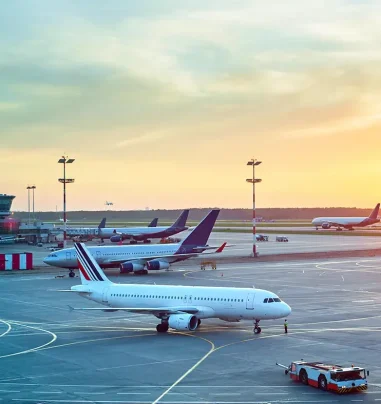 View of airport runway with planes parked at sunrise